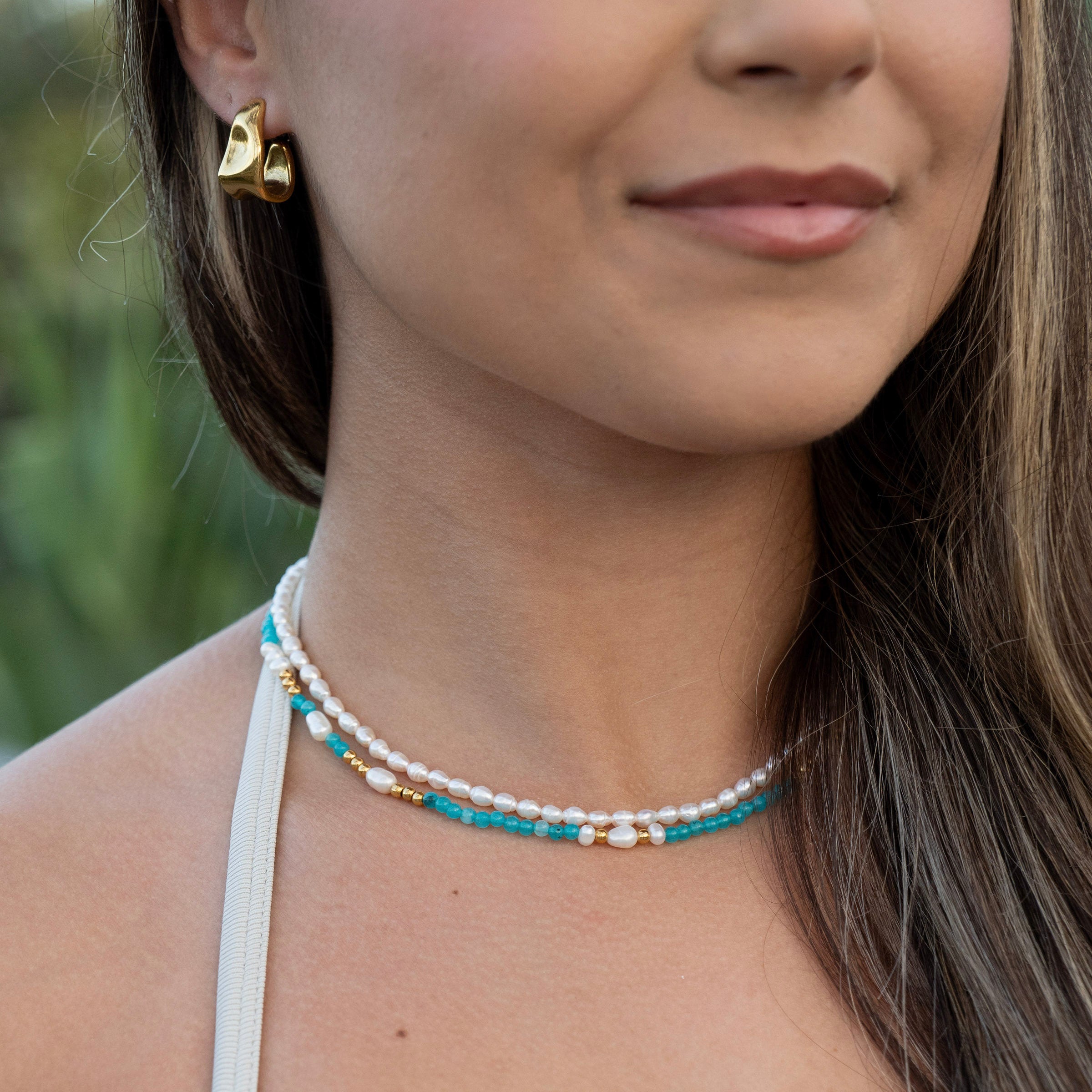 Ocean-inspired necklace stack featuring turquoise stones and pearl details