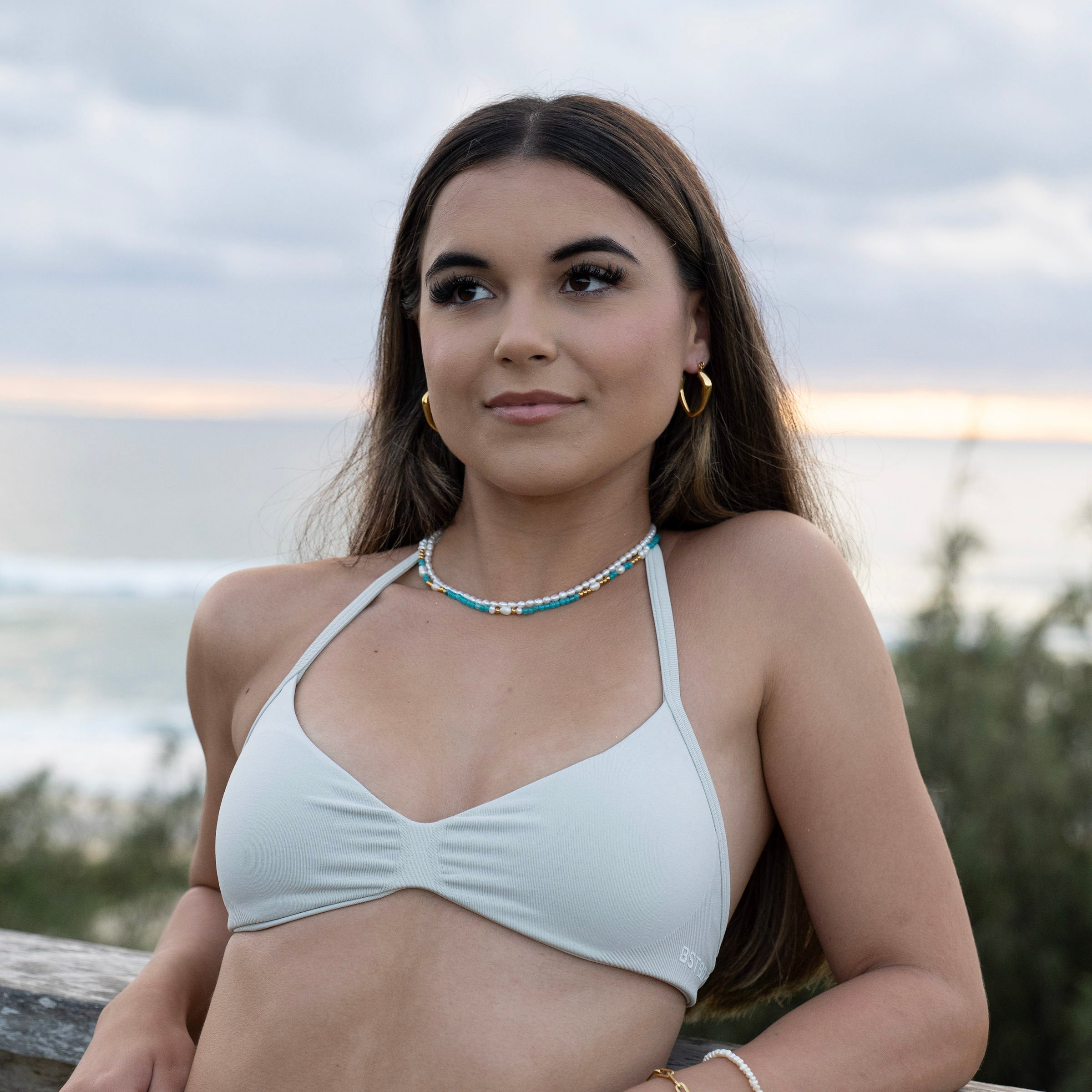 Gold PVD waterproof hoop earrings worn by model, tarnish-free stainless steel everyday earrings styled for beach and ocean wear