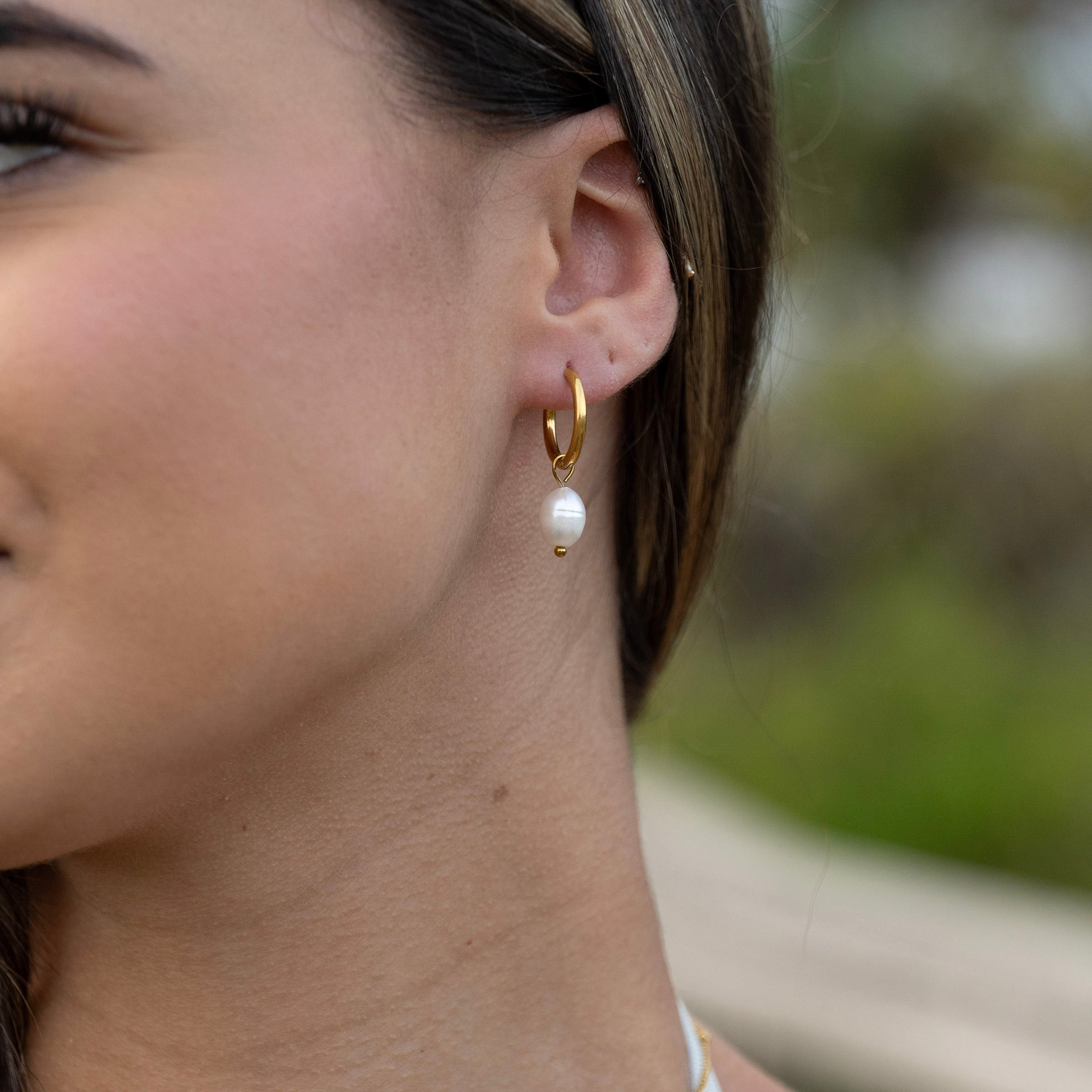 Gold PVD waterproof pearl drop hoop earrings worn on ear, tarnish-free stainless steel hoops with freshwater pearl pendant