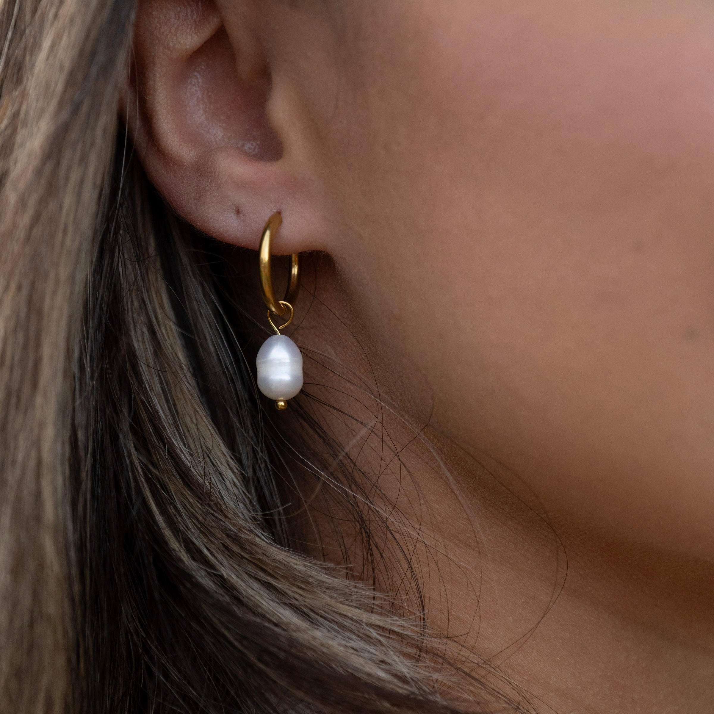 Pearl drop hoop earrings worn close-up, waterproof gold PVD stainless steel earrings styled for beach and everyday wear