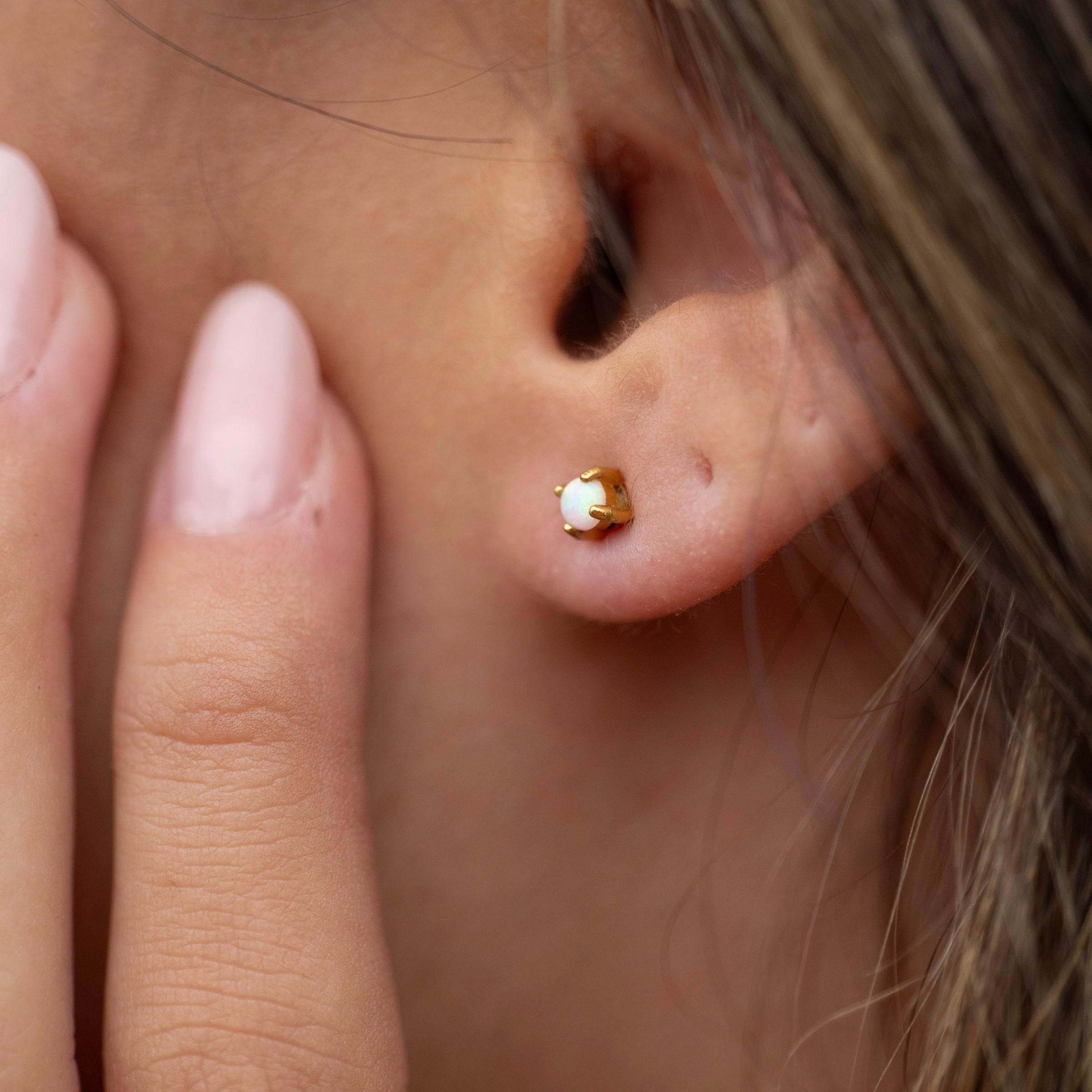 Waterproof gold PVD opal stud earrings on ear, tarnish-free stainless steel earrings