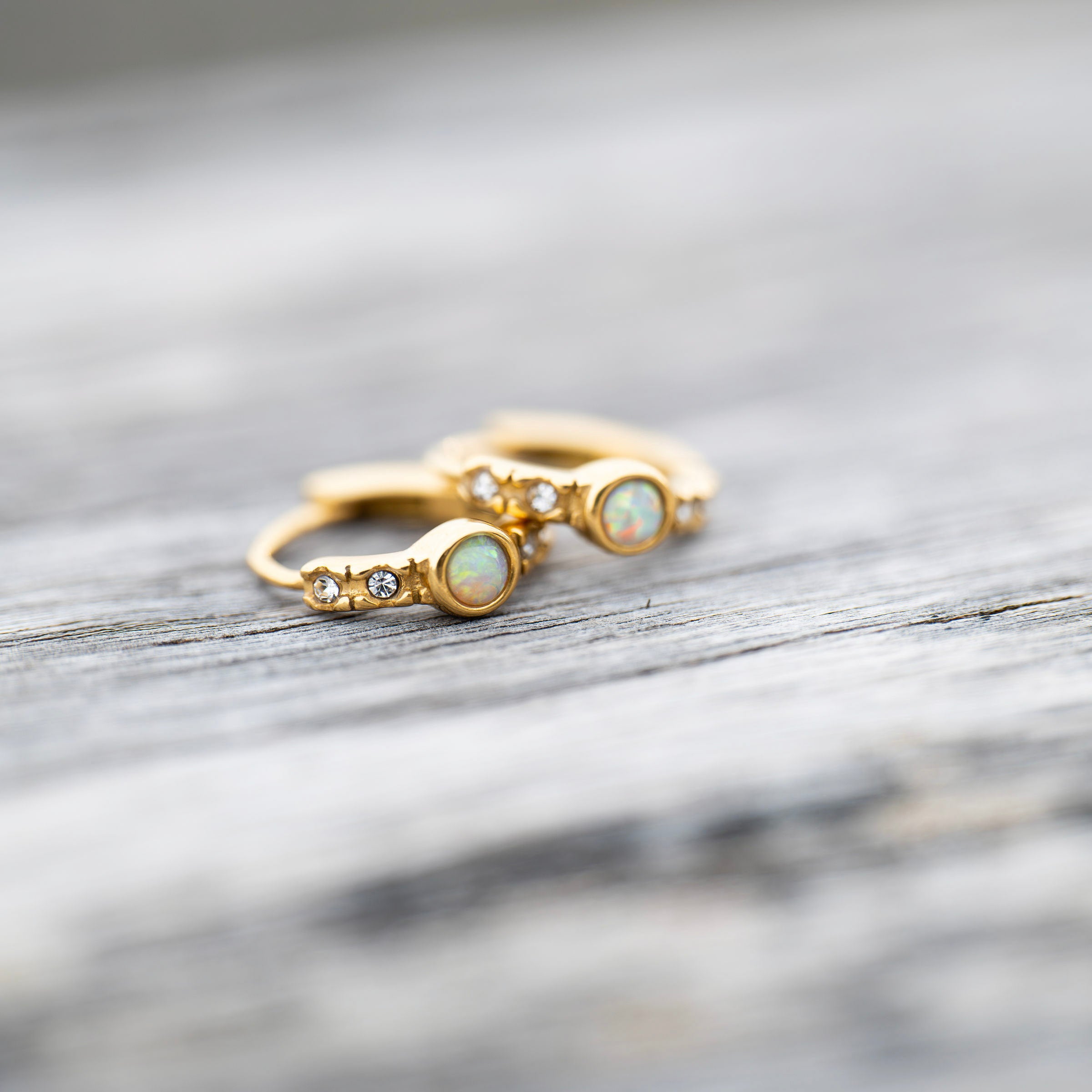 Waterproof gold PVD opal huggie earrings on ear, tarnish-free stainless steel earrings