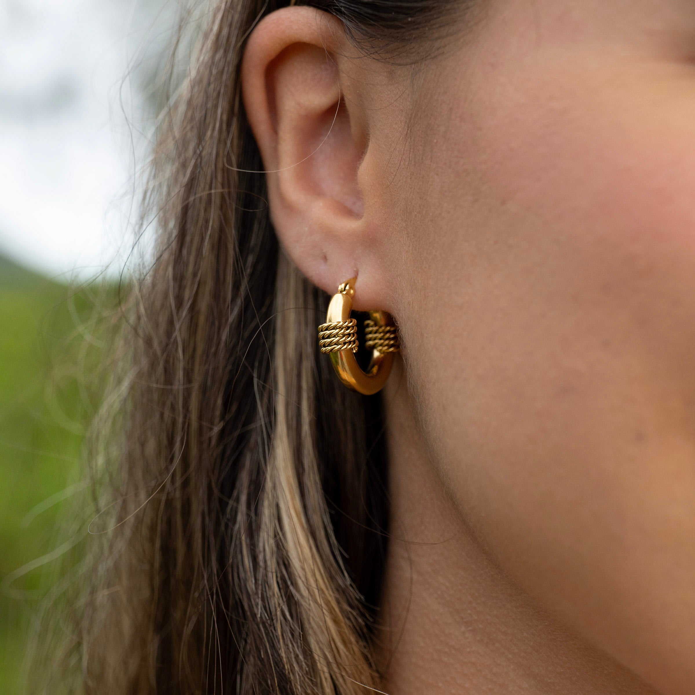 Waterproof gold PVD hoop earrings on ear, tarnish-free stainless steel rope-style hoops