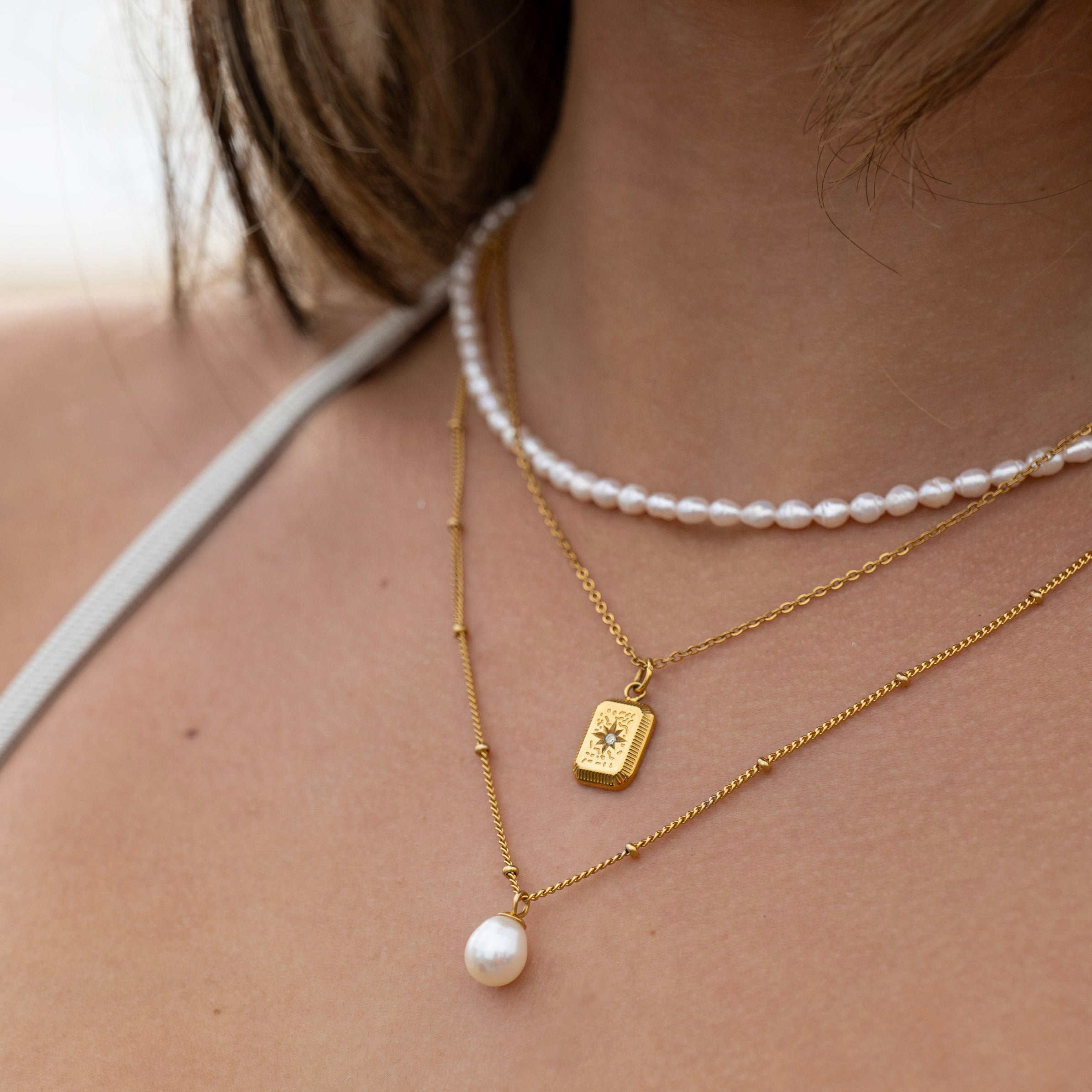 Layered gold and pearl necklace set worn on model