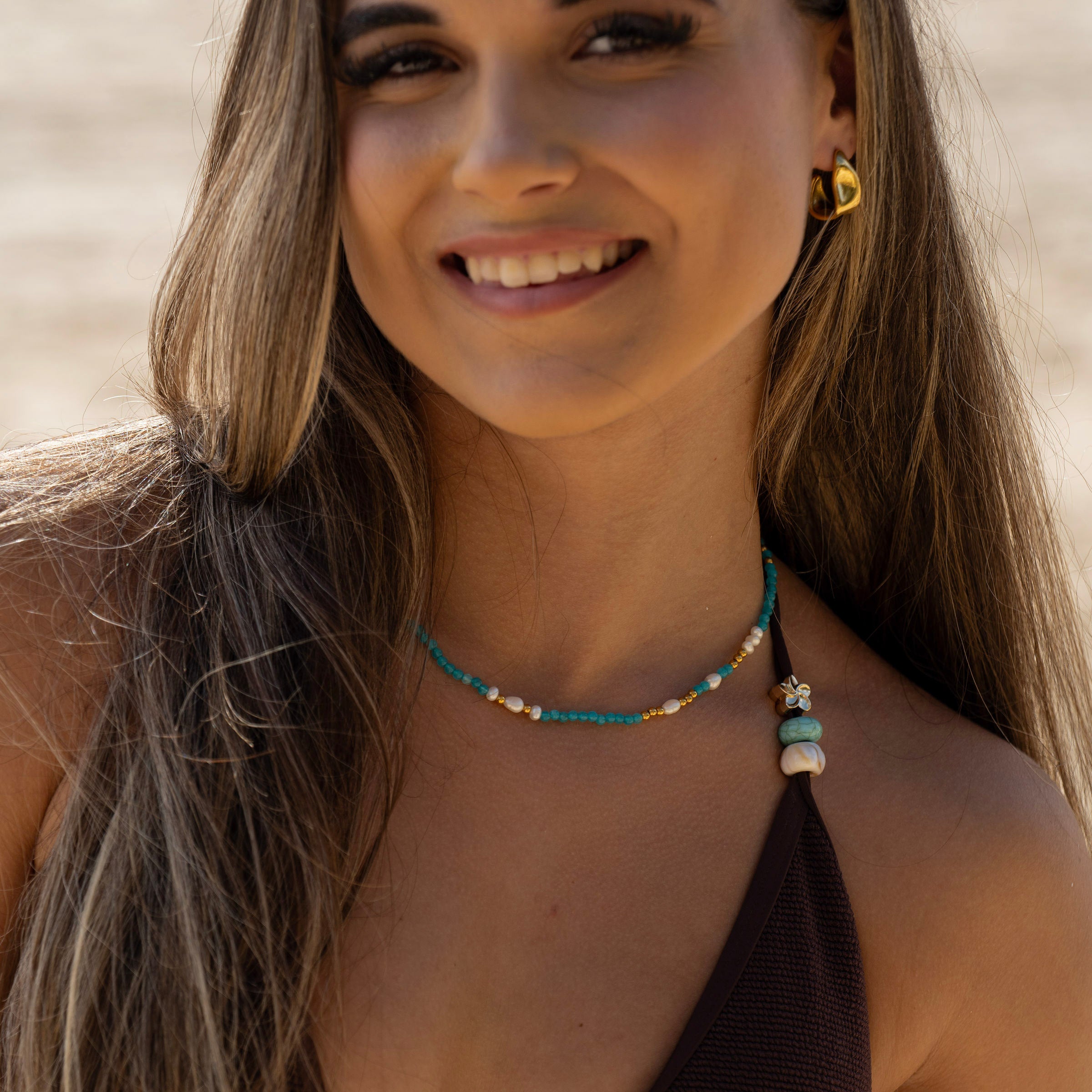 Layered gold necklace stack with pearl and turquoise beads on model