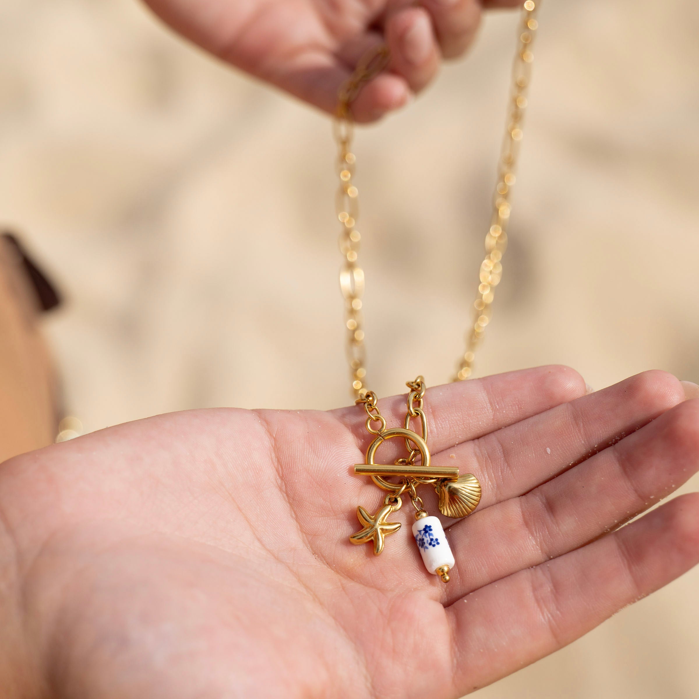 Coastal charm gold necklace layered on sunlit skin