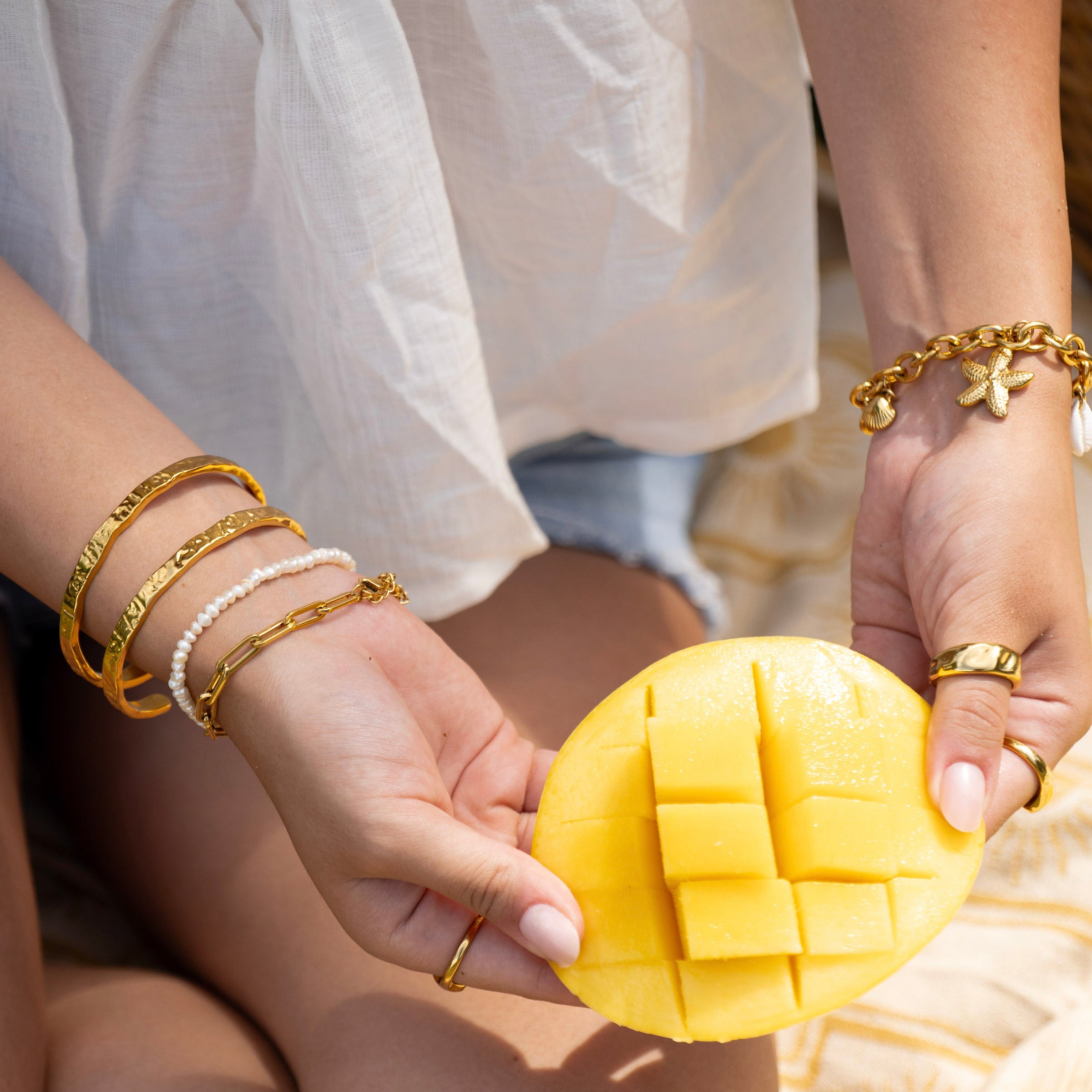 Gold sun signet ring in 18K PVD stainless steel, waterproof tarnish-free jewellery worn on hand holding sunglasses