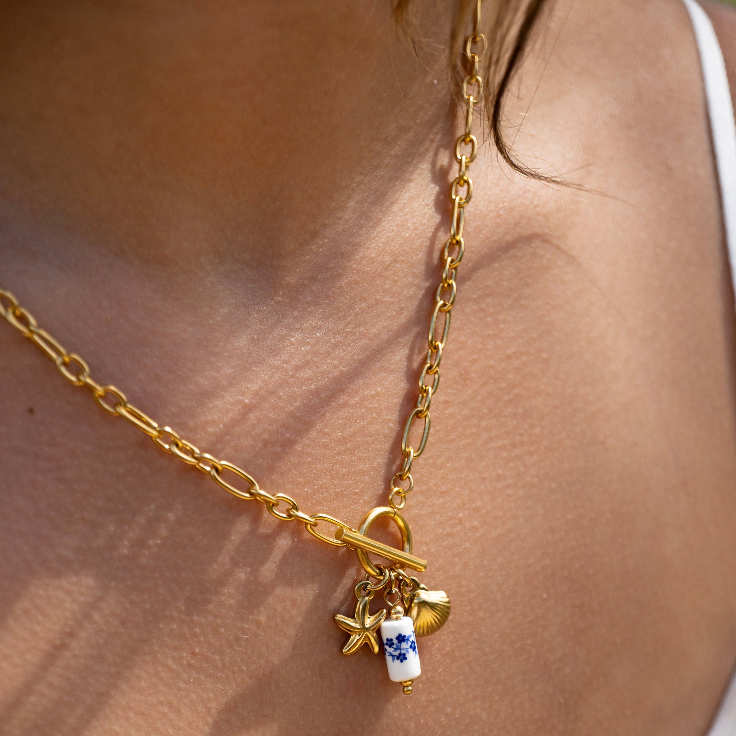 Waterproof gold T-bar necklace with ocean charms worn on model