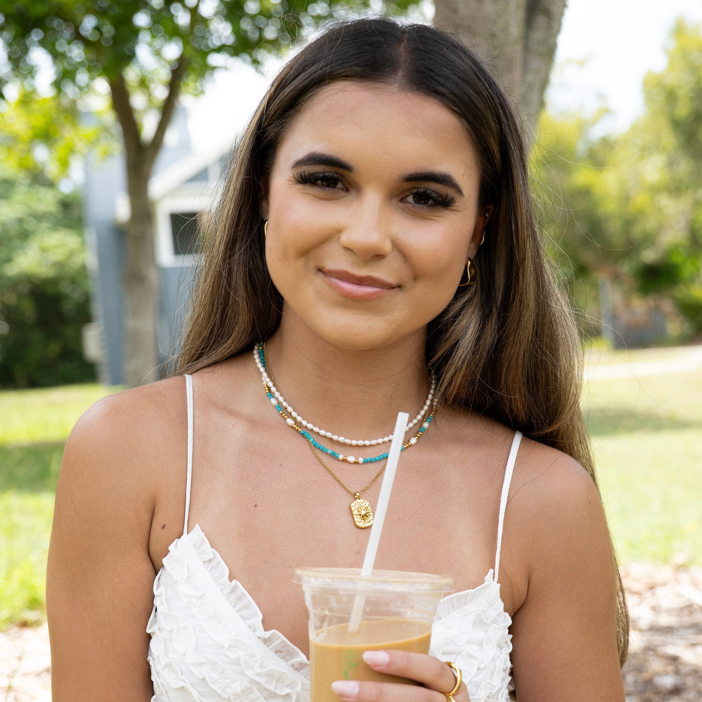 Coastal-inspired necklace stack featuring freshwater pearl choker, turquoise bead necklace and gold pendant
