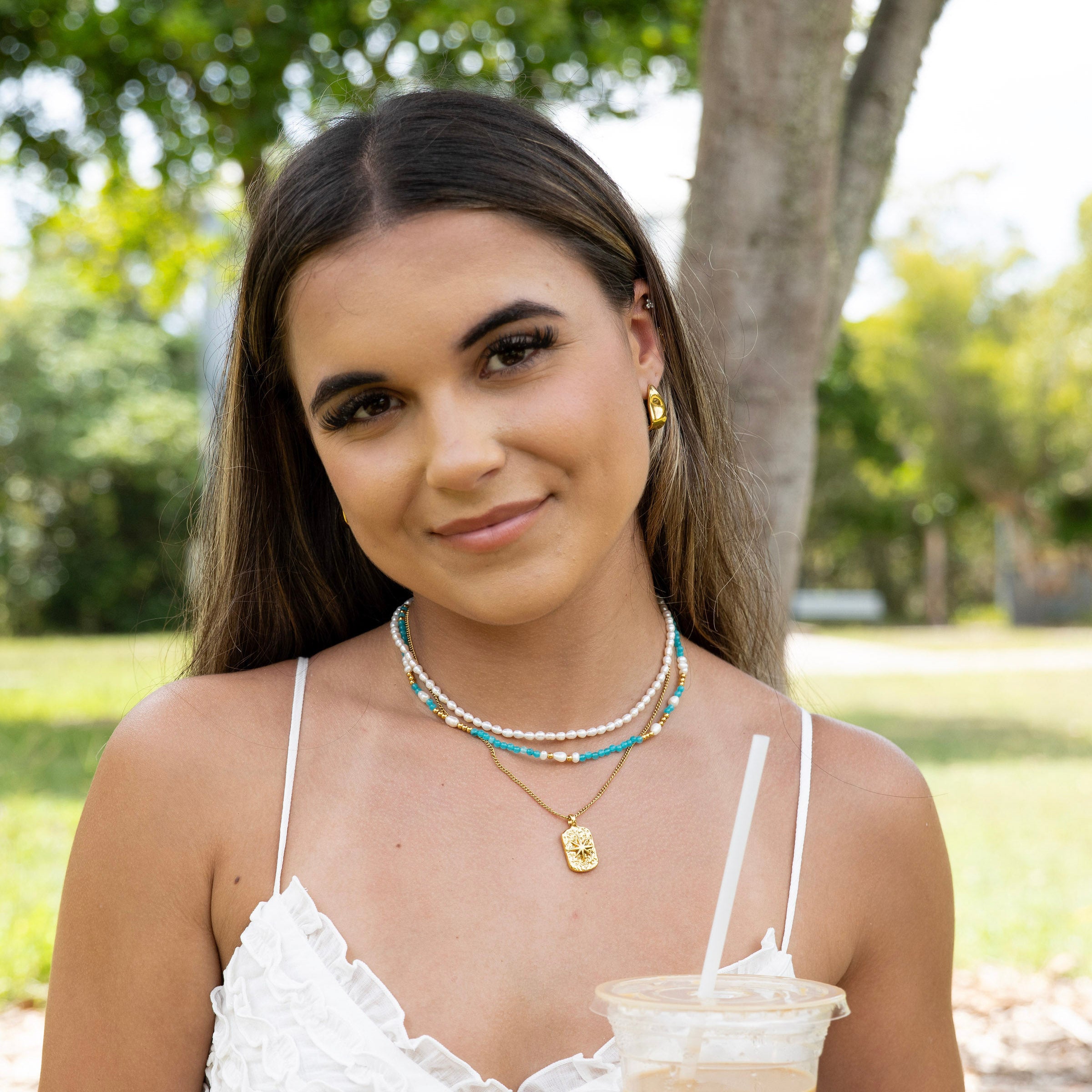 Waterproof gold and pearl necklace stack styled on model in natural light