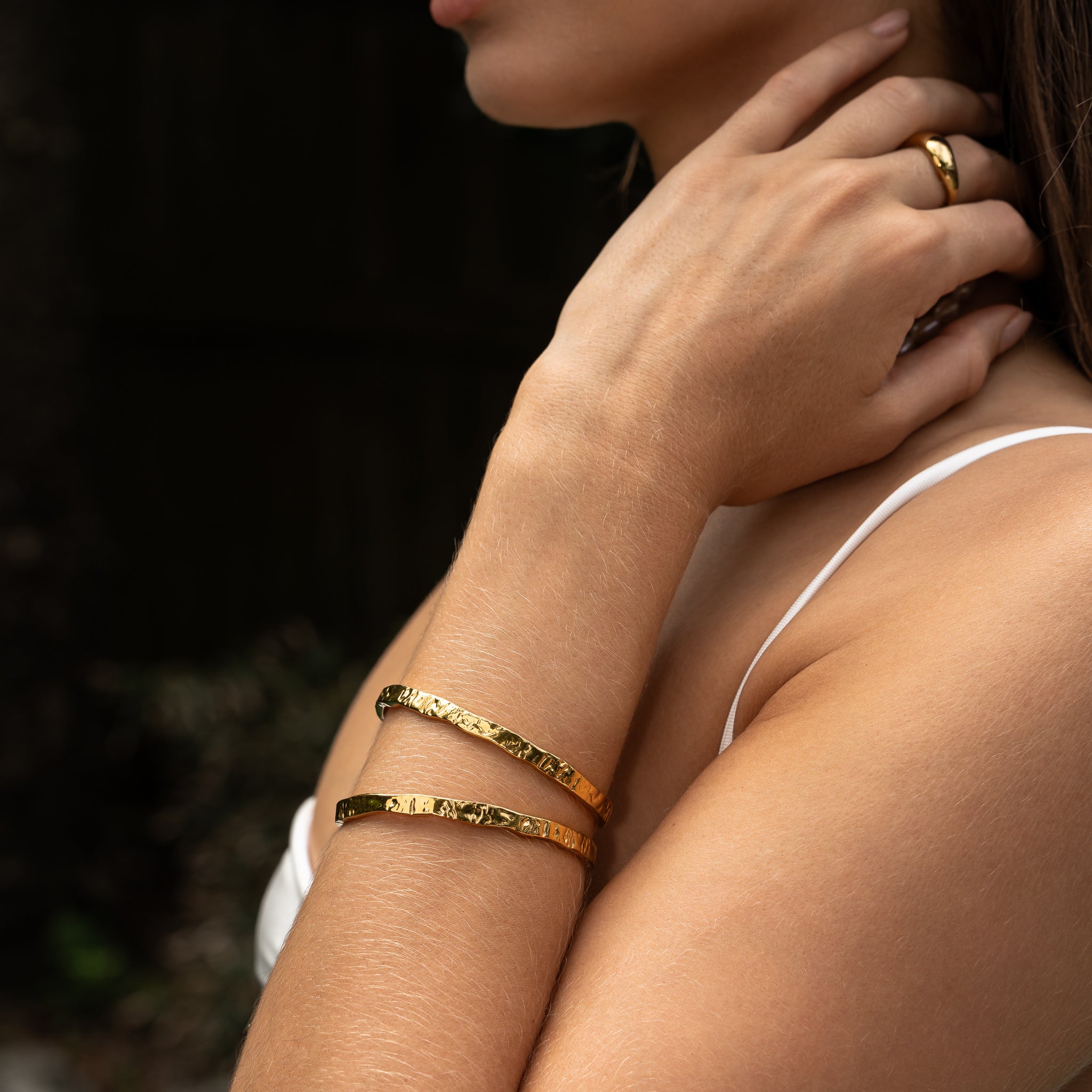 Model styling the Erosion Cuff Bracelet — coastal-inspired gold cuff with irregular carved texture.