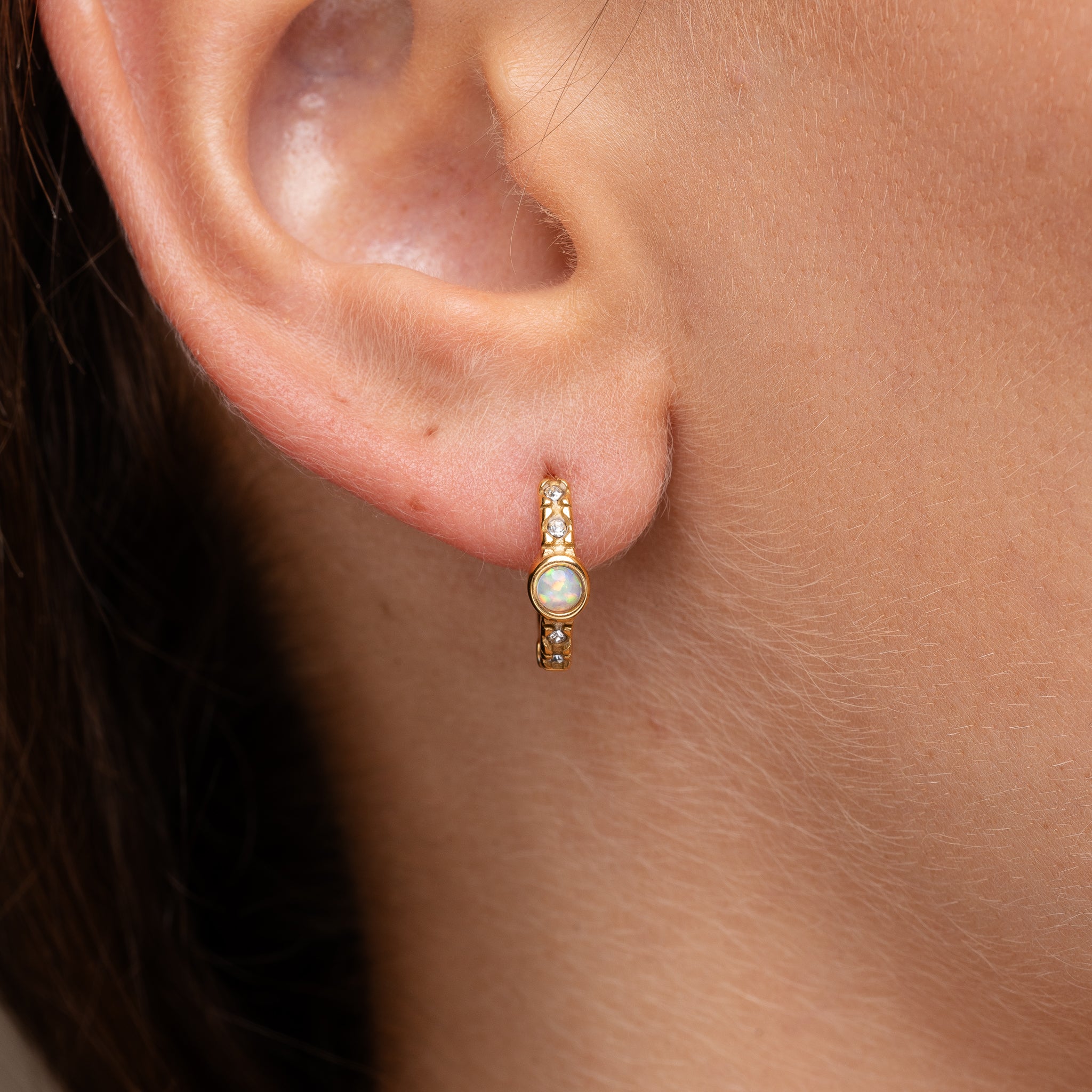 Gold opaline huggie earrings worn on ear