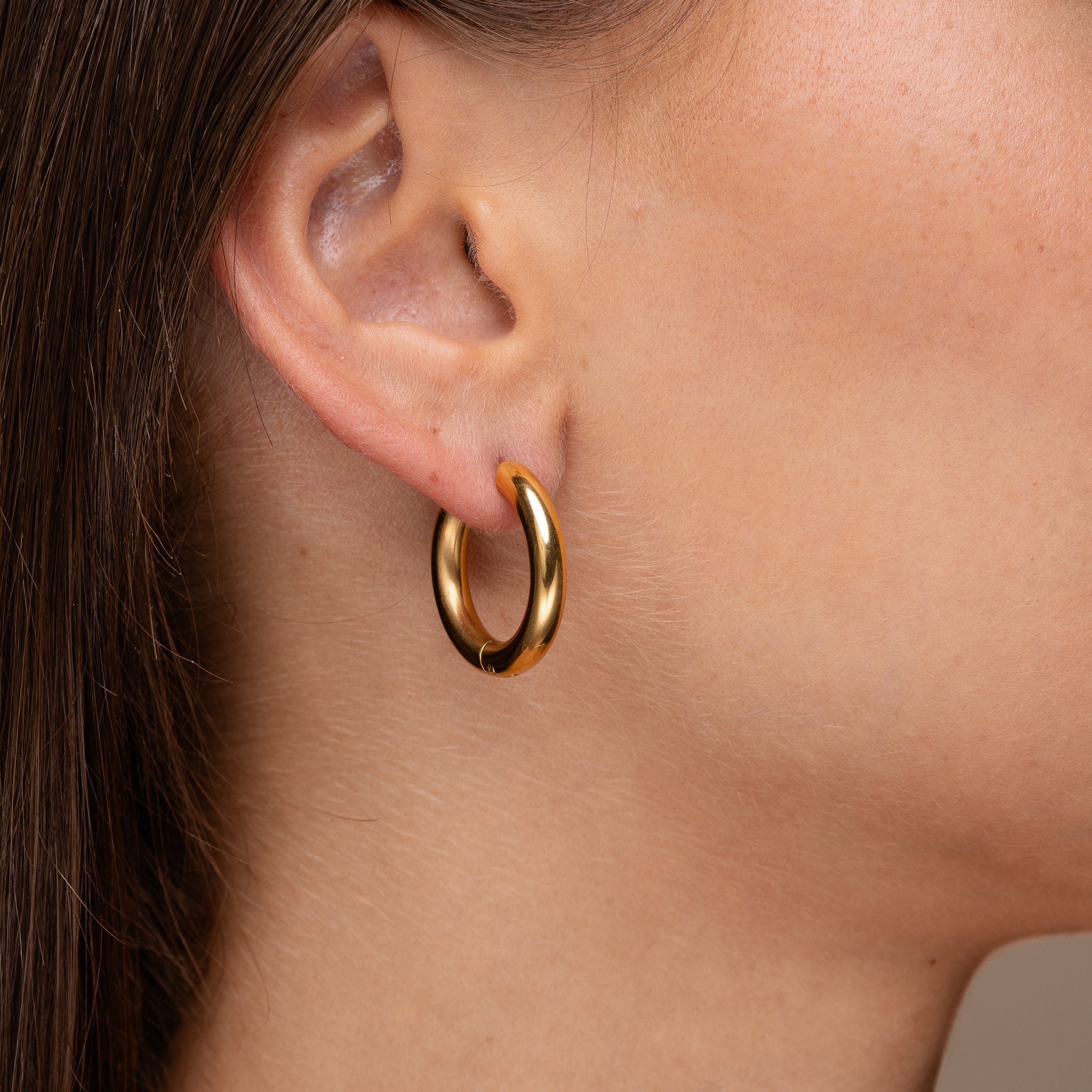Model wearing Solace Curve Hoops gold earrings